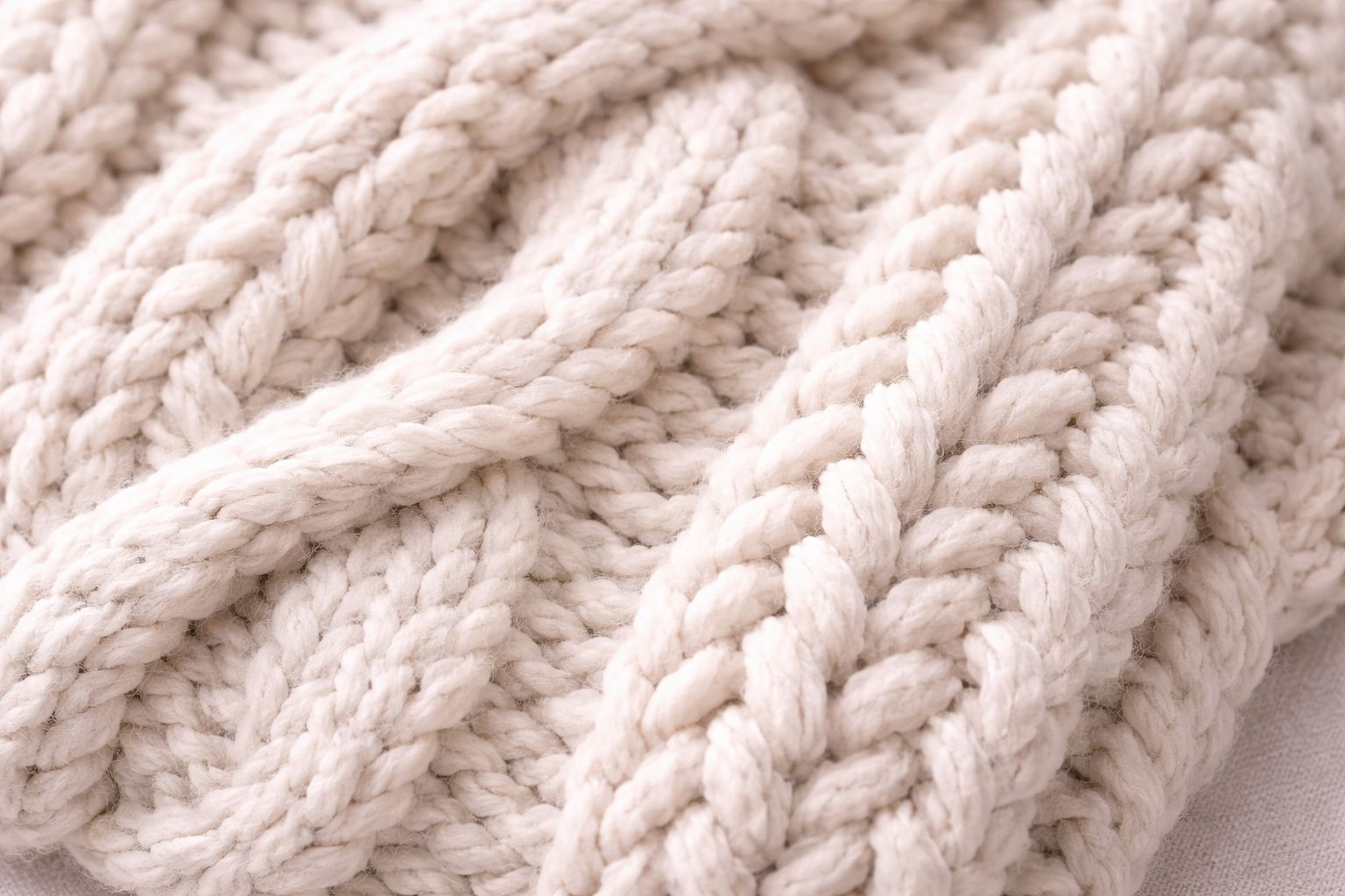 An image showing a close-up of a chunky, low-gauge knit sweater, highlighting the thick yarn and deep texture