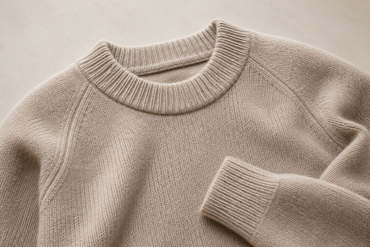 A close-up shot of a luxurious Merino wool sweater in a neutral color, highlighting its intricate knit texture and quality.