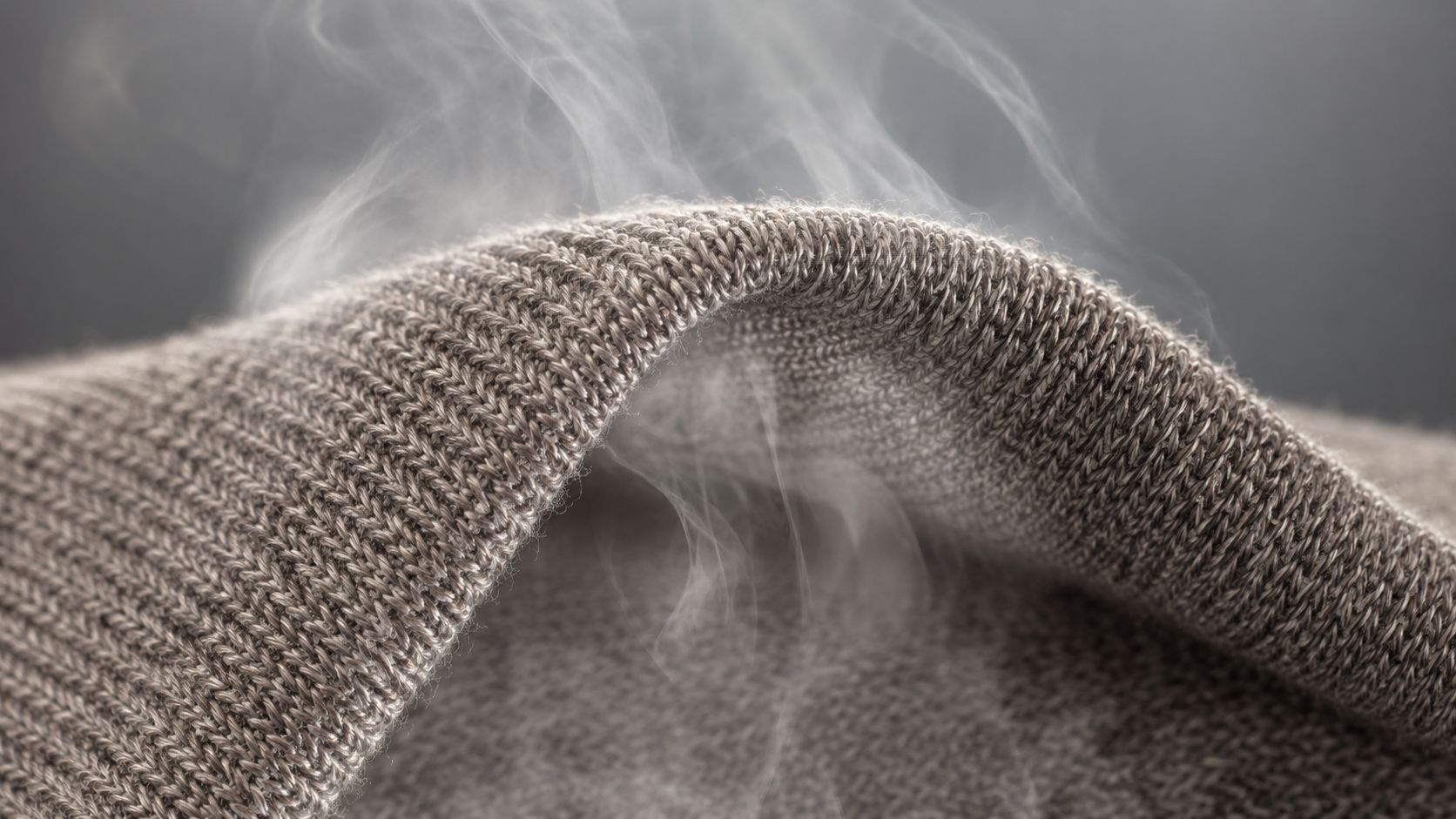 A macro shot of steam passing through a fine Merino wool knit fabric, demonstrating its breathability.